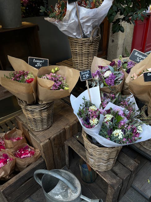 A display of fresh flower bouquets arranged in woven wicker baskets at a florist shop, with pink, purple, and white blooms including carnations, gypsophila, and chrysanthemums, wrapped in brown craft