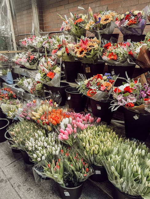 An array of fresh flower bouquets arranged on display at Marylebone Florist, including tulips, roses, lilies, and anemones in shades of pink, red, white, orange, and purple. The flowers are presented